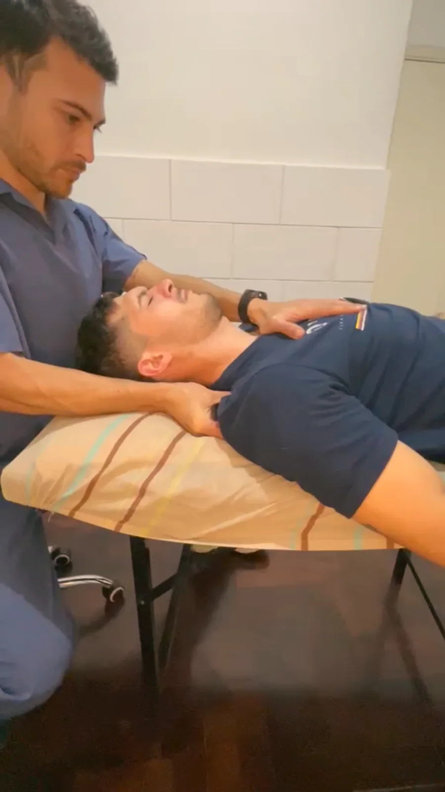 Christian trabajando el cuello de un paciente en la camilla.