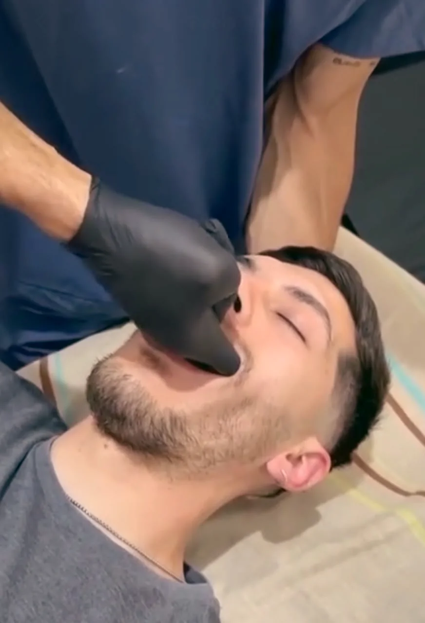 Christian evaluando la mandíbula de un paciente en la camilla.